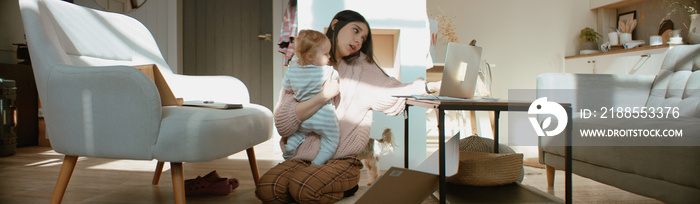 Young mother working from home surrounded by daughter and dog, having a work call. Stay home, quarantine remote work. Shot on RED Dragon