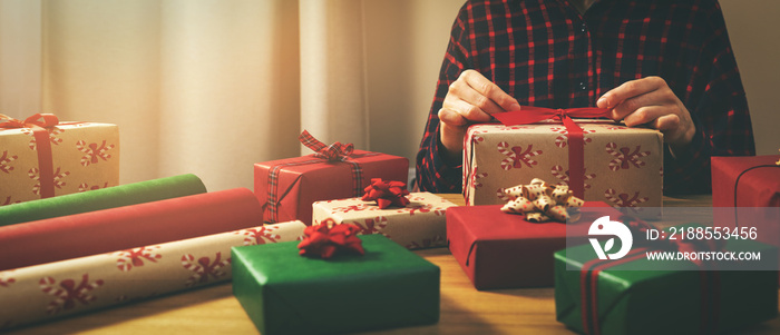 woman wrapping gifts at home. tie a bow