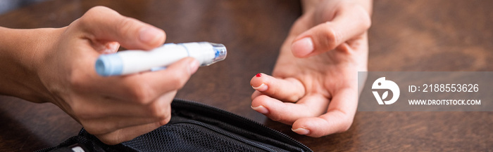 panoramic shot of woman holding blood lancet near finger with blood