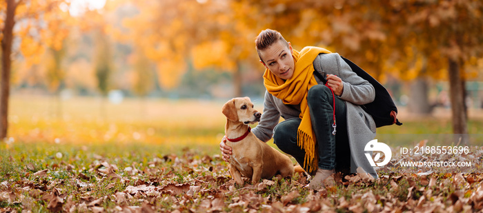 Woman talking to a dog at the park in autumn