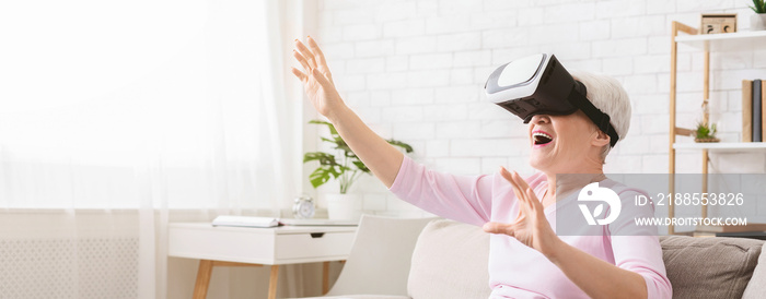 Modern senior woman using VR glasses at home