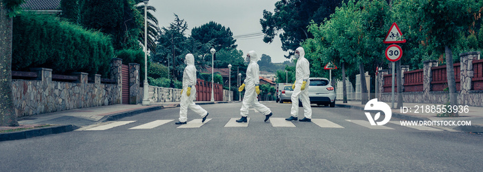 Group of people in bacteriological protection suits crossing a crosswalk on an empty street