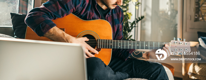 Portrait of an young man learning to play guitar at home