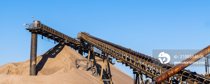 Panoramic view of heavy metal construction of open pit gravel plant sand quarry big rusty conveyor belt material excavating and crushing. Industrial machinery factory equipment steel background