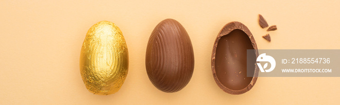 Top view of chocolate easter eggs on beige background, panoramic shot