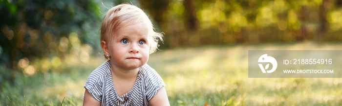 Cute baby girl crawling on ground in park outdoors. Adorable child toddler learning to walk. Healthy physical development. Funny kid. Authentic lifestyle happy childhood. Web banner header.