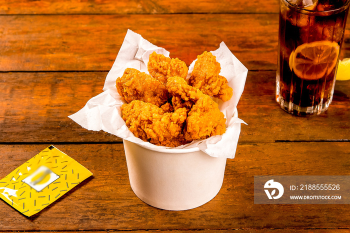 Crispy Boneless chicken wings Bites 6 pieces with drink and ketchup served in a basket isolated on wooden board on grey background side view of fastfood