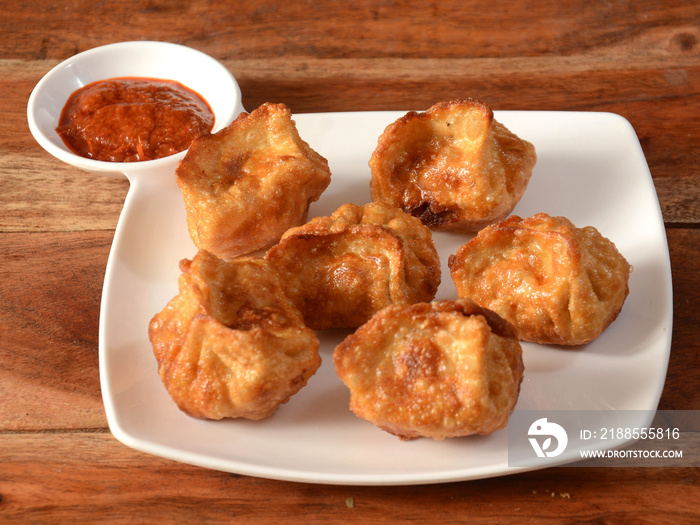 Chicken fried momo with sauce served over a rustic wooden background, selective focus