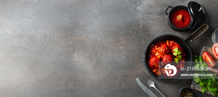 Spanish cuisine large banner. Albondigas or meatballs in with tomato sauce with ingridients on dark concrete background. Copy space