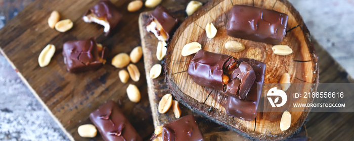 Selective focus. Macro. Chocolate bars with peanuts and caramel. Peanut. Wood background. Sweets, chocolate, nuts.