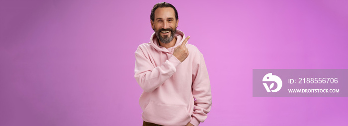 Charming friendly happy mature man 50s bearded grey hair laughing happily pointing upper left corner behind showing proudly family members standing purple background having fun stay positive