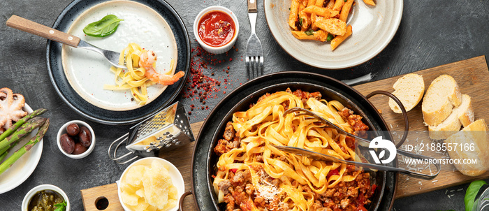 Assortment of Italian pasta with traditional sauces for dinner on dark background. Homemade food concept