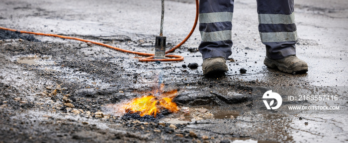 road worker prepare pothole with gas torch flame for repairing. copy space