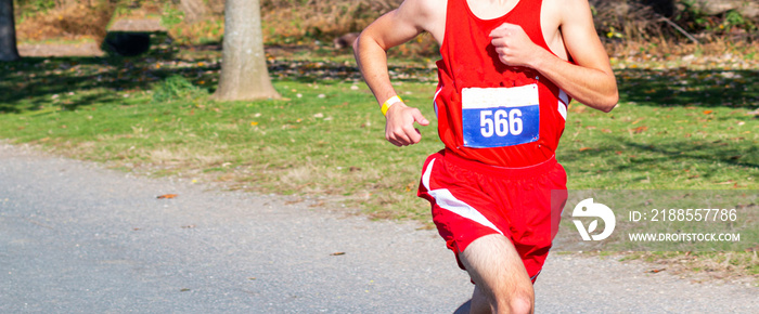 High school cross country runnerfinishing a 5K on a gravel straightaway with plenty of copy spzce behind him