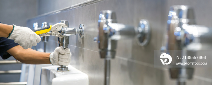 Hand of handyman or plumber is using a wrench to fix or repair leaking water pipes, faucets or valves in toilet bowls and sinks in restroom or bathroom