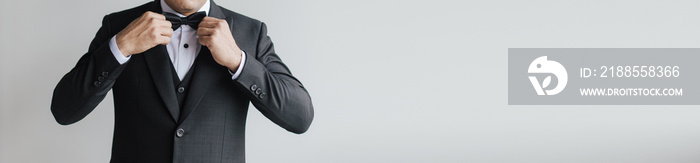 Close up of a man with a black suit doing a preparation and pose fixing or wearing a neck tie.