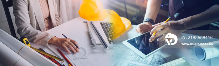 Two colleagues discussing data working and tablet, laptop with on on architectural project at construction site at desk in office