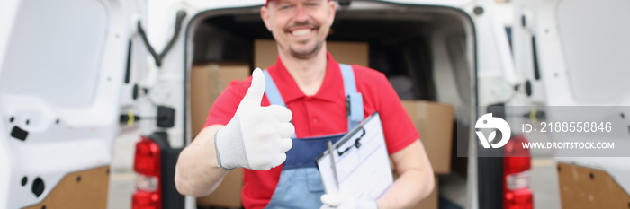 Cheerful delivery service worker show thumbs up gesture in front of car