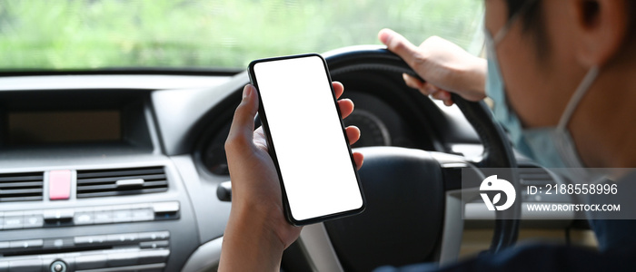 Close up over shoulder view of young man using mobile phone while driving car.