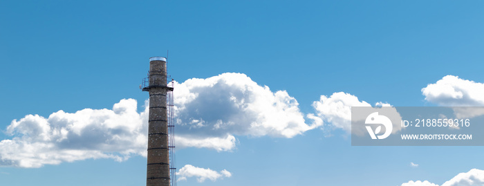 A large brick chimney on a background of blue sky with clouds