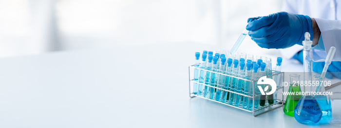 Lab assistant, a medical scientist, a chemistry researcher holds a glass tube through the blood sample, does a chemical experiment and examines a patient’s blood sample. Medicine and research concept.