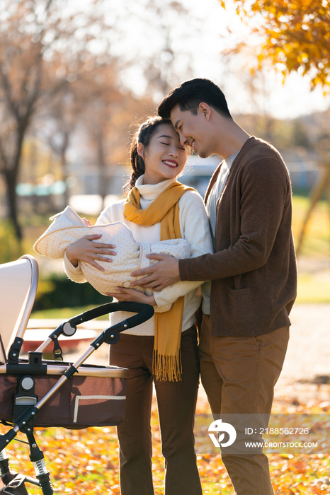 年轻夫妻推着婴儿车散步