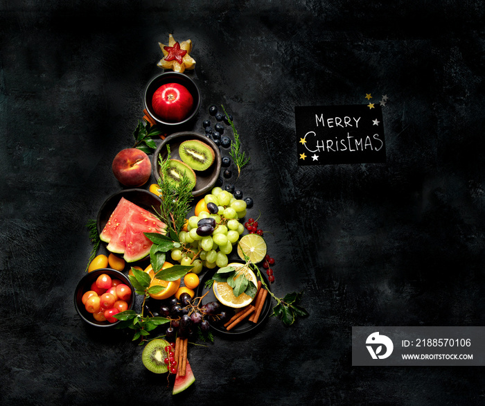 Christmas tree made of fruits on dark background.