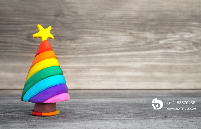 Playful Christmas concept. Handmade miniature Christmas tree in rainbow colors. Soft wood background