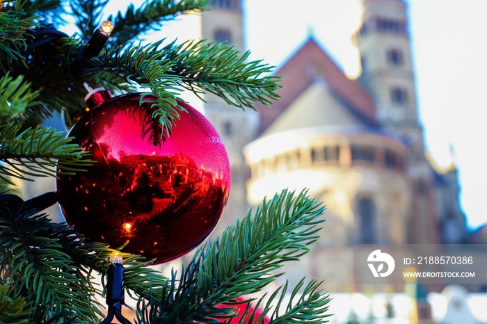 Close up of Christmas tree branch with red shiny ball decoration. Blurred basilica background. Chris