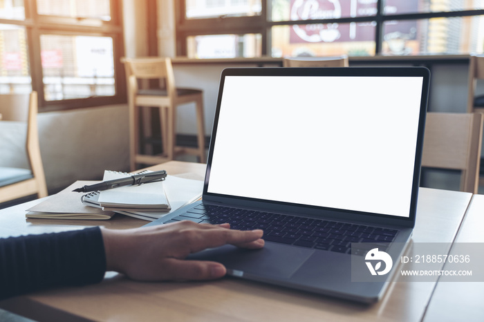 Mockup image of  a hand using and touching laptop touchpad with blank white desktop screen while sit