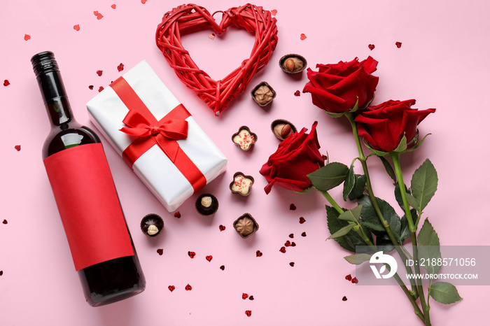 Bottle of wine, chocolate candies, rose flowers and heart on pink background. Valentines Day celebr