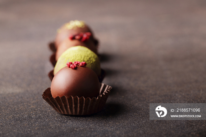 Chocolate craft candies, dessert on dark background.