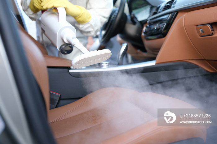 The specialist cleans the chair in the car with a washing vacuum cleaner