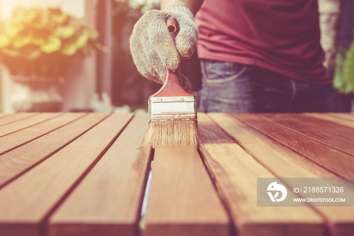 Paintbrush in hand and painting on the wooden table. Retro and v