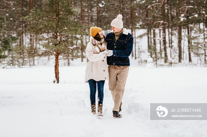 people, love and leisure concept - happy smiling couple walking in winter forest