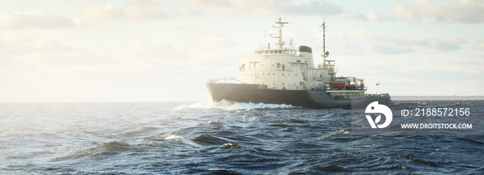 Soviet icebreaker in an open sea under dramatic sunset clouds. Freight transportation, global commun