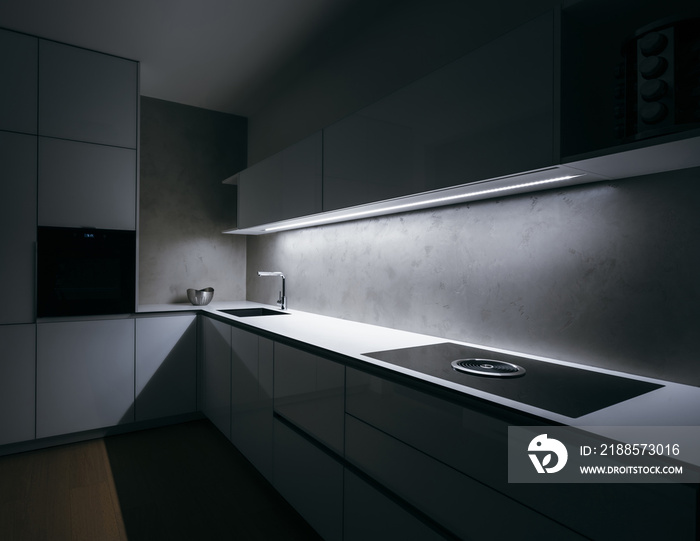 Modern white kitchen of corner shape in minimalist design, during night, with light strip turned on,