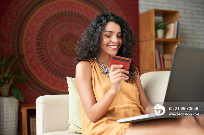 Cheerful attractive young woman buying something online with credit card