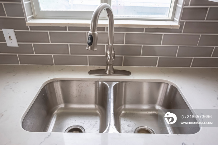 Double bowl stainless steel sink undermounted on the white kitchen countertop