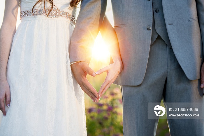 Bride and groom making a heart shape with their hands