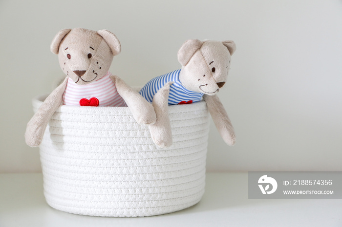 A pair of his and hers teddy bears trying to get out of or looking out of basket. Stuffed toy.