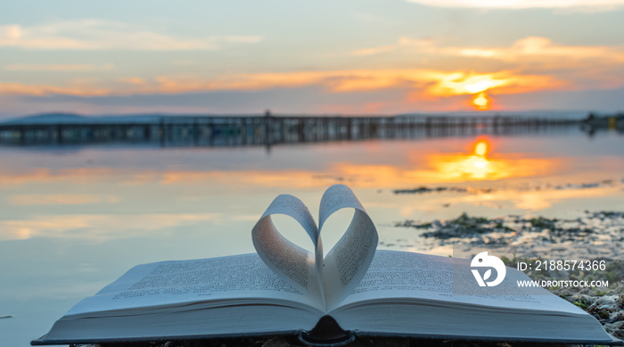 Livre plié en forme de cœur avec lever de soleil sur un étang de Camargue, France.