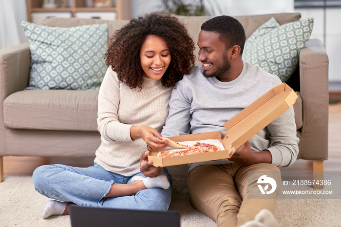 leisure, people and food concept - happy african american couple with laptop computer eating takeawa