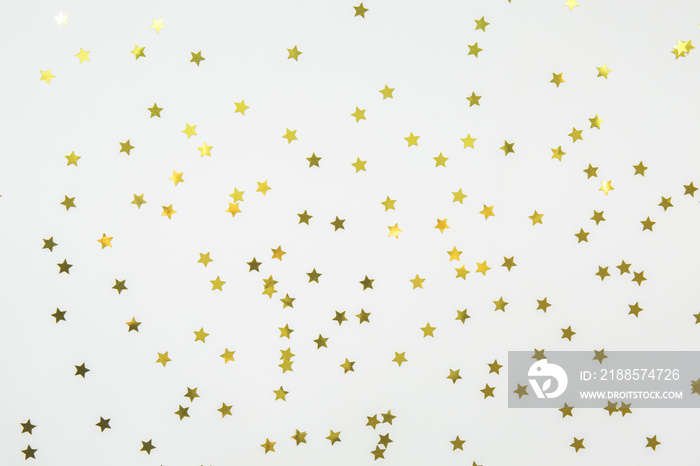 Golden star sprinkles on white. Festive holiday background. Celebration concept