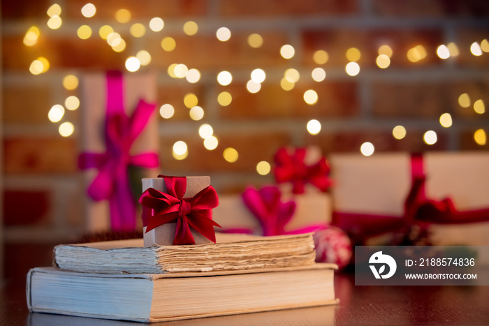 gift box and books on background with fairy lights and gifts in bokeh. Christmas Holiday season