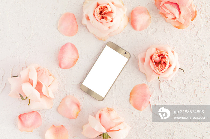 Top view of pink female desk with modern gold mobile phone with white blank screen and flowers