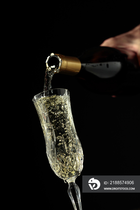 Sparkling wine is poured from a bottle into a glass.