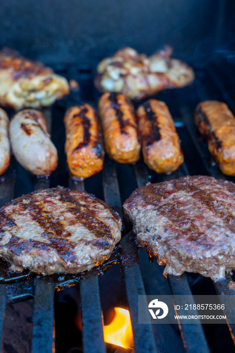 Burgers and sausages cooking on a BBQ grill