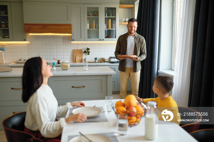 Happy family with child eating pizza sitting at dining table