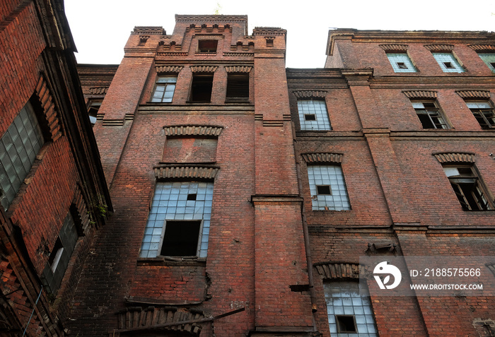 Broken windows in an old building on the grounds of an abandoned factory.